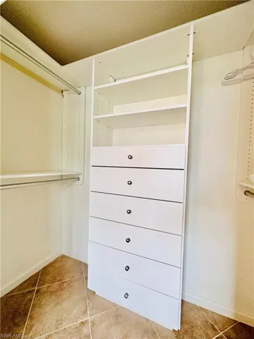 Spacious master closet with light tile patterned floors