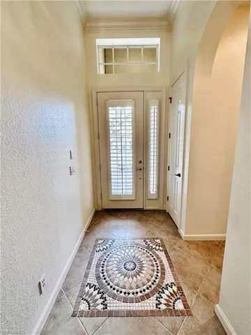 Tiled foyer featuring ornamental molding