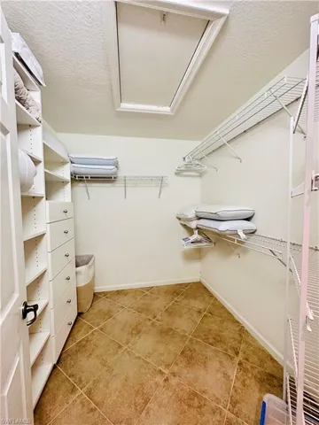 Walk in master closet featuring light tile patterned flooring