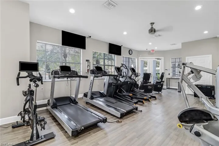 Exercise room with french doors, a wealth of natural light, ceiling fan, and light wood-type flooring