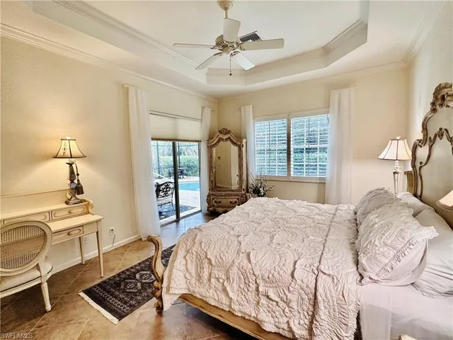 Tiled bedroom with a raised ceiling, access to outside, ornamental molding, and ceiling fan