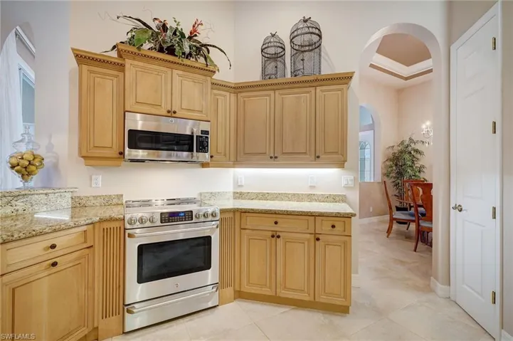 Kitchen featuring light brown cabinetry, appliances with stainless steel finishes, light stone countertops, and light tile patterned flooring