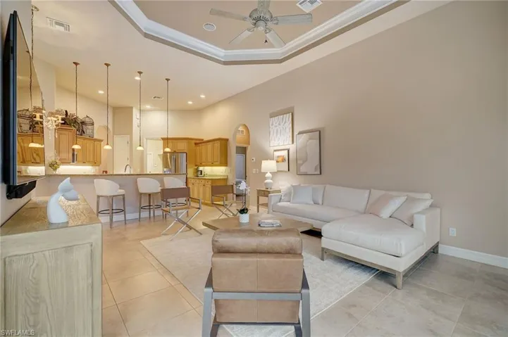 Great room featuring ceiling fan, light tile patterned flooring, a tray ceiling, and ornamental molding