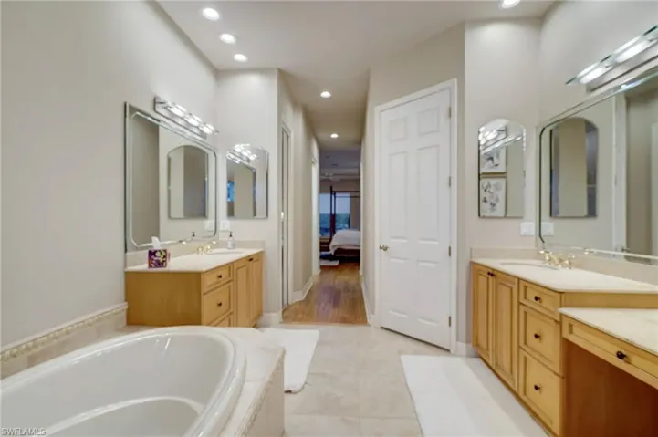 Bathroom with tiled bath, vanity, and tile patterned floors