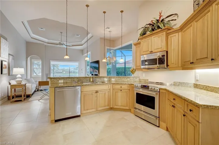 Kitchen with pendant lighting, sink, a raised ceiling, light brown cabinets, and appliances with stainless steel finishes