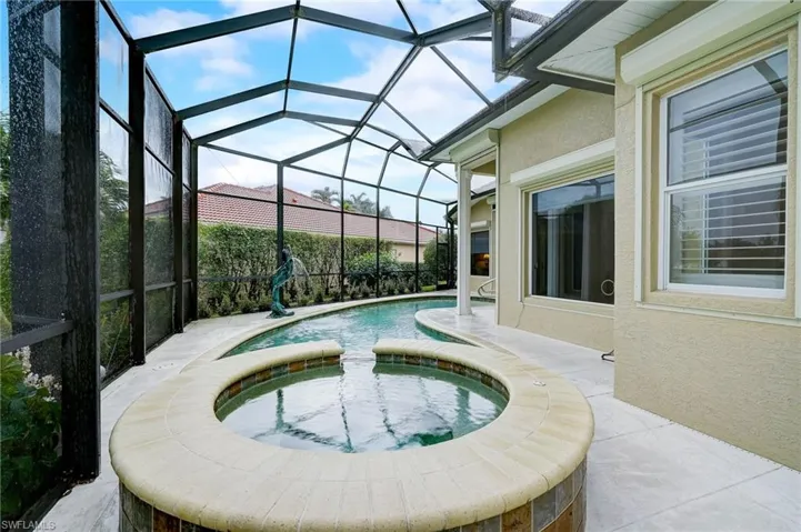 View of swimming pool featuring glass enclosure, an in ground hot tub, and a patio area