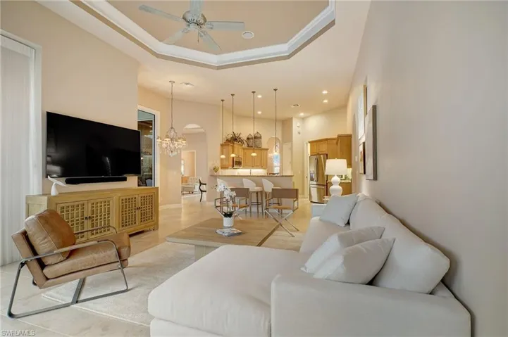 Tiled great room featuring ceiling fan with notable chandelier, a high ceiling, and crown molding