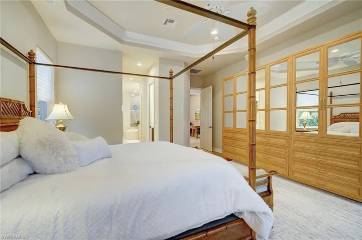 Bedroom featuring a raised ceiling, connected bathroom, and ornamental molding