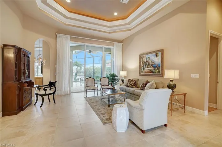 Living room featuring light tile patterned flooring, ornamental molding, ceiling fan, and plenty of natural light
