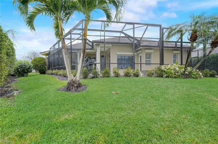 Rear view of house with a lawn and a lanai