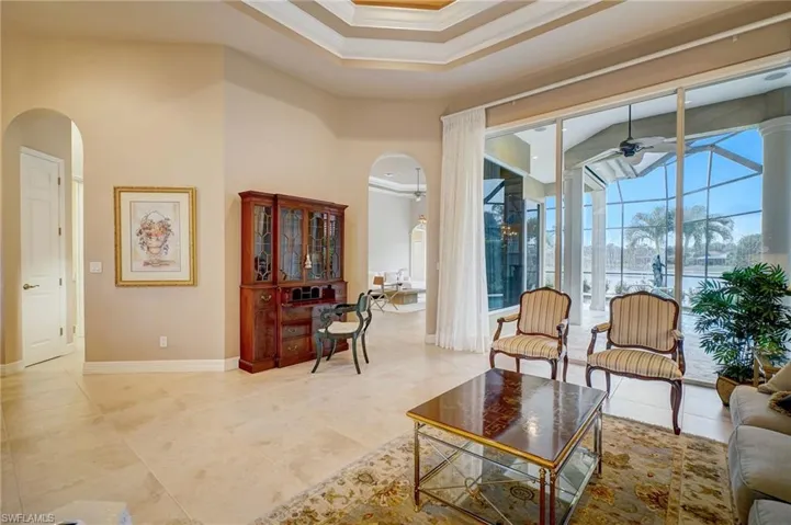 Living room featuring ceiling fan, ornamental molding, and a high ceiling