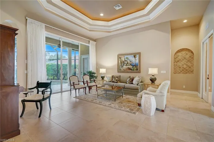 Living room with a raised ceiling, light tile patterned floors, and crown molding