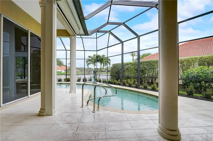 View of pool featuring glass enclosure and a patio area