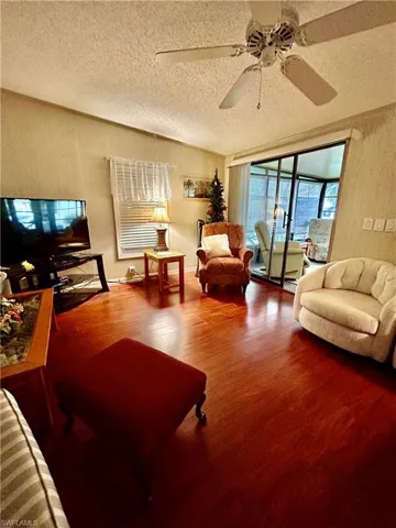 Living room with ceiling fan, hardwood / wood-style flooring, and a textured ceiling