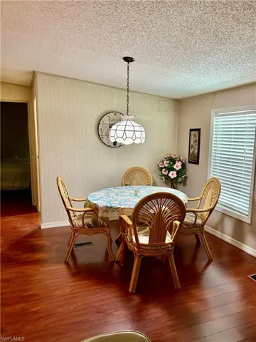 Dining area with a textured ceiling and dark hardwood / wood-style flooring
