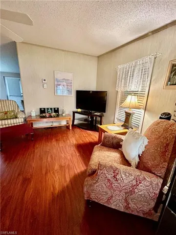 Living room with a textured ceiling, hardwood / wood-style flooring, and ceiling fan