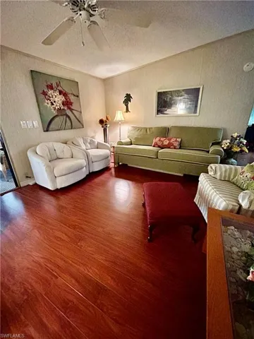 Living room featuring a textured ceiling, ceiling fan, and dark hardwood / wood-style floors