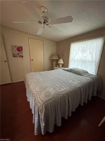 Bedroom with a textured ceiling, hardwood / wood-style flooring, and ceiling fan