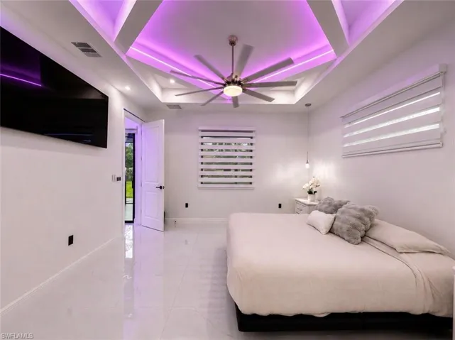 Tray ceiling with recessed lighting and LED accents, large ceiling fan, white tile flooring, and multiple windows with horizontal blinds
