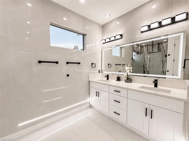 Dual vanity with integrated sinks, quartz countertop, and white cabinetry featuring matte black hardware