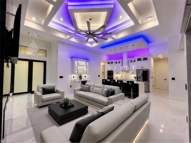 Open-concept living space featuring a tray ceiling with integrated lighting, a modern ceiling fan, and large format tile flooring