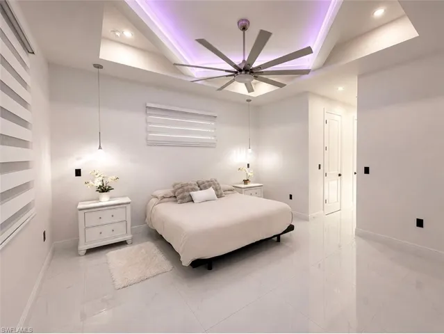 Spacious room featuring a tray ceiling with recessed lighting and a contemporary ceiling fan
