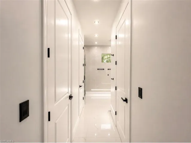 Hallway featuring white paneled doors with matte black hardware