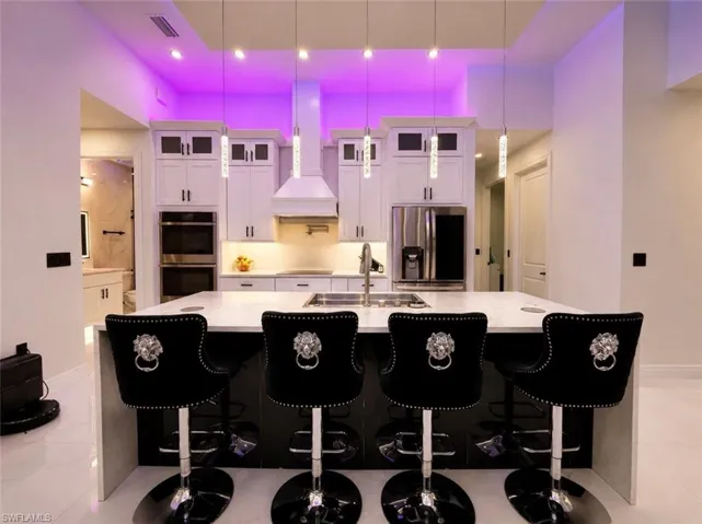 Kitchen island featuring a white countertop, under-cabinet lighting, and built-in stainless steel appliances