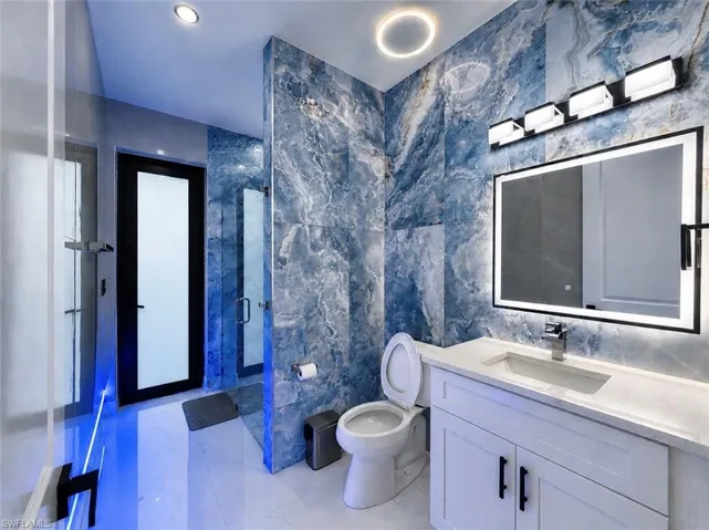 Modern bathroom featuring blue marble-look wall tiling and white floor tiles