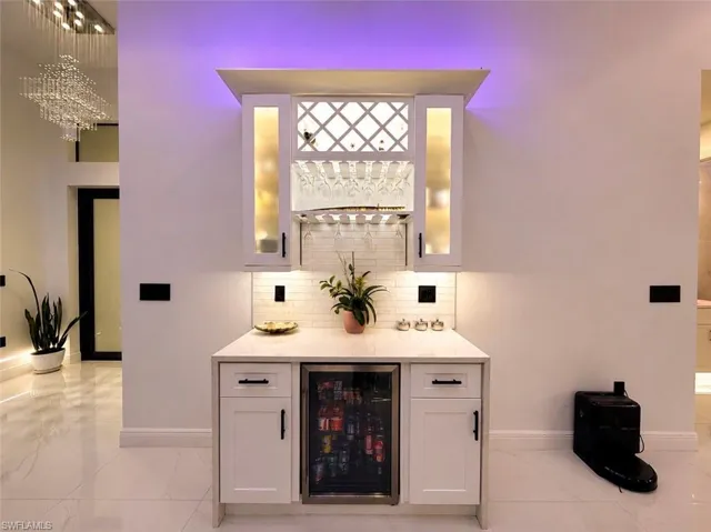 Built-in wet bar featuring white shaker cabinetry, an integrated beverage cooler, and a light-colored countertop
