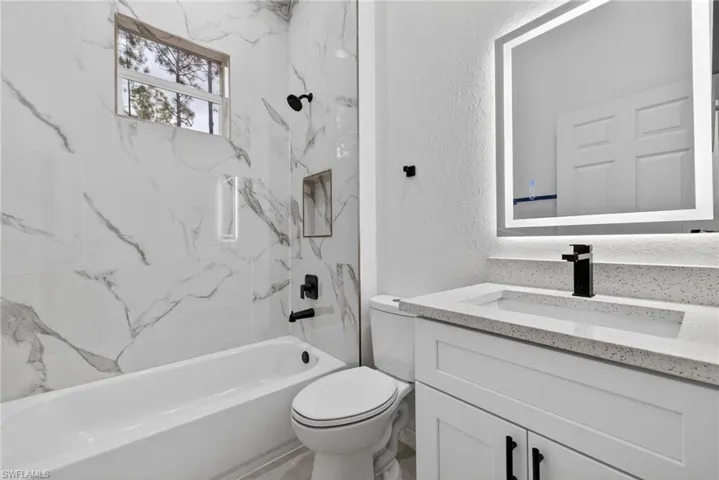 Bathroom featuring a textured wall, vanity, and shower / washtub combination