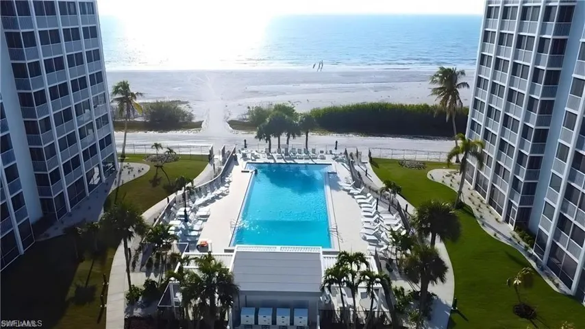 Outdoor swimming pool with  - Virtually Edited Imagesurrounding lounge chairs, manicured lawn, and direct beach access