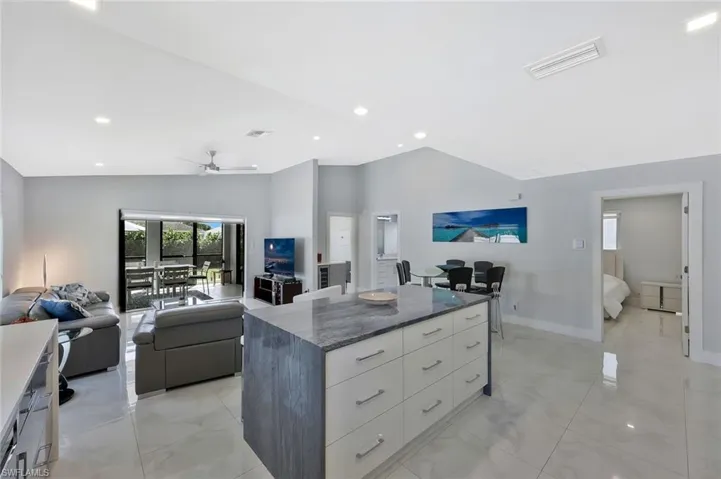 Kitchen featuring a center island, open floor plan, light marble finish flooring, dark stone countertops, and modern cabinets