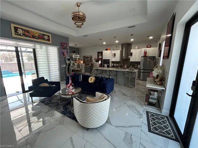 Living room featuring a tray ceiling and light marble finish floors