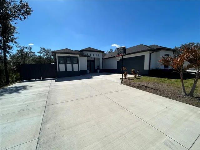 Prairie-style house with a gate, concrete driveway, stucco siding, and a garage