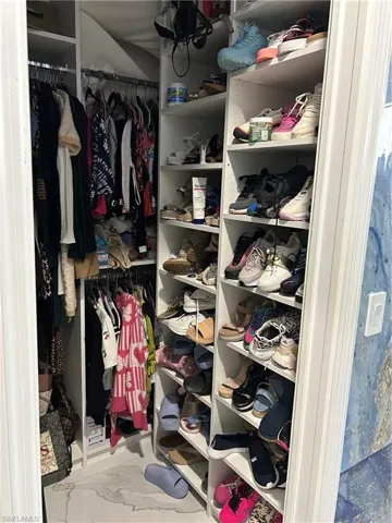 Walk in closet featuring light marble finish flooring