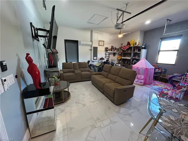 Living area with a garage, light marble finish flooring, and electric panel