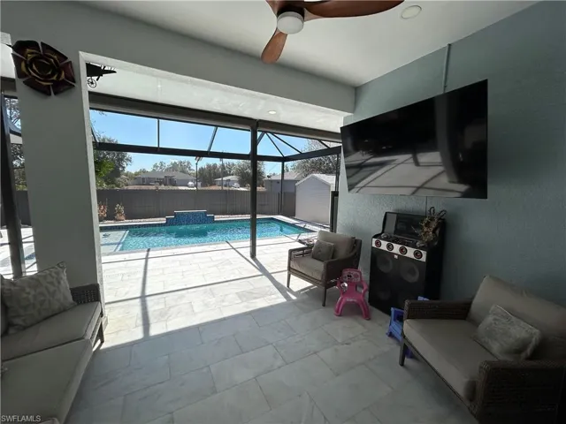 View of pool featuring glass enclosure, a sunroom, patio surround, and a fenced backyard