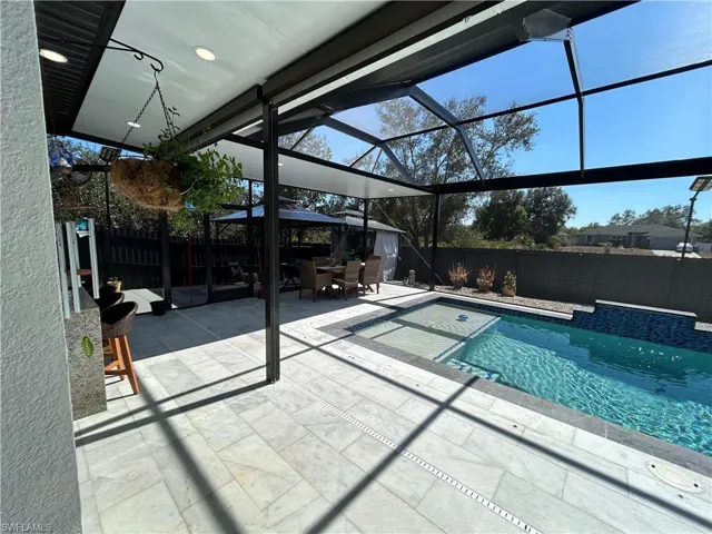 View of pool with a fenced backyard, patio surround, a lanai, outdoor dining area, and a sunroom