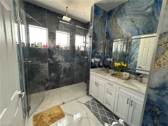 Bathroom featuring double vanity and a marble finish shower