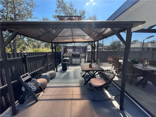Deck with outdoor dining area, a fenced backyard, a patio area, a gazebo, and a grill