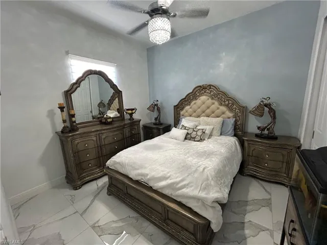 Bedroom with a ceiling fan and light marble finish floors