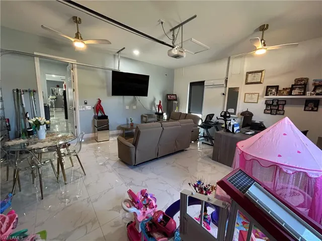 Living room featuring ceiling fan, marble finish flooring, electric panel, a garage, and recessed lighting