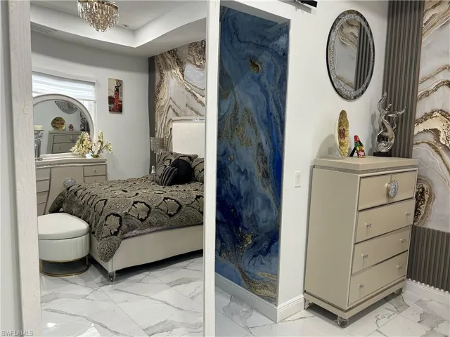 Bedroom featuring light marble finish floors and hanging lights