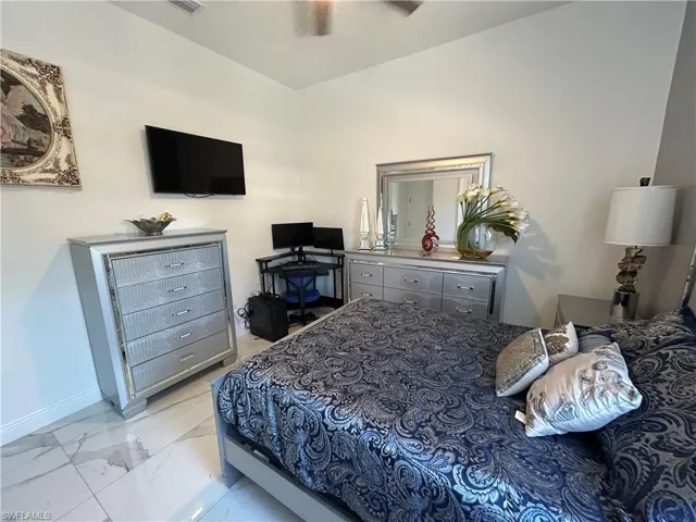 Bedroom featuring light marble finish floors and ceiling fan