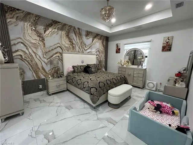 Bedroom with hanging lights and marble look tile flooring