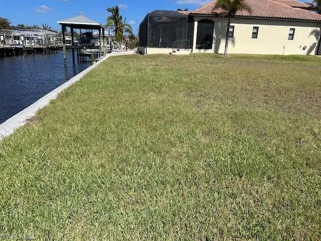 View of green lawn featuring a water view and a lanai