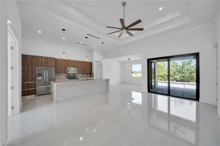 Unfurnished living room with a raised ceiling, a towering ceiling, ceiling fan, and recessed lighting