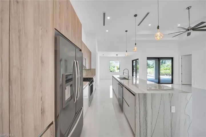 Kitchen with modern cabinets, stainless steel appliances, a large island, light stone counters, and recessed lighting