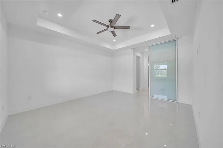 Unfurnished room featuring a raised ceiling, a ceiling fan, and recessed lighting